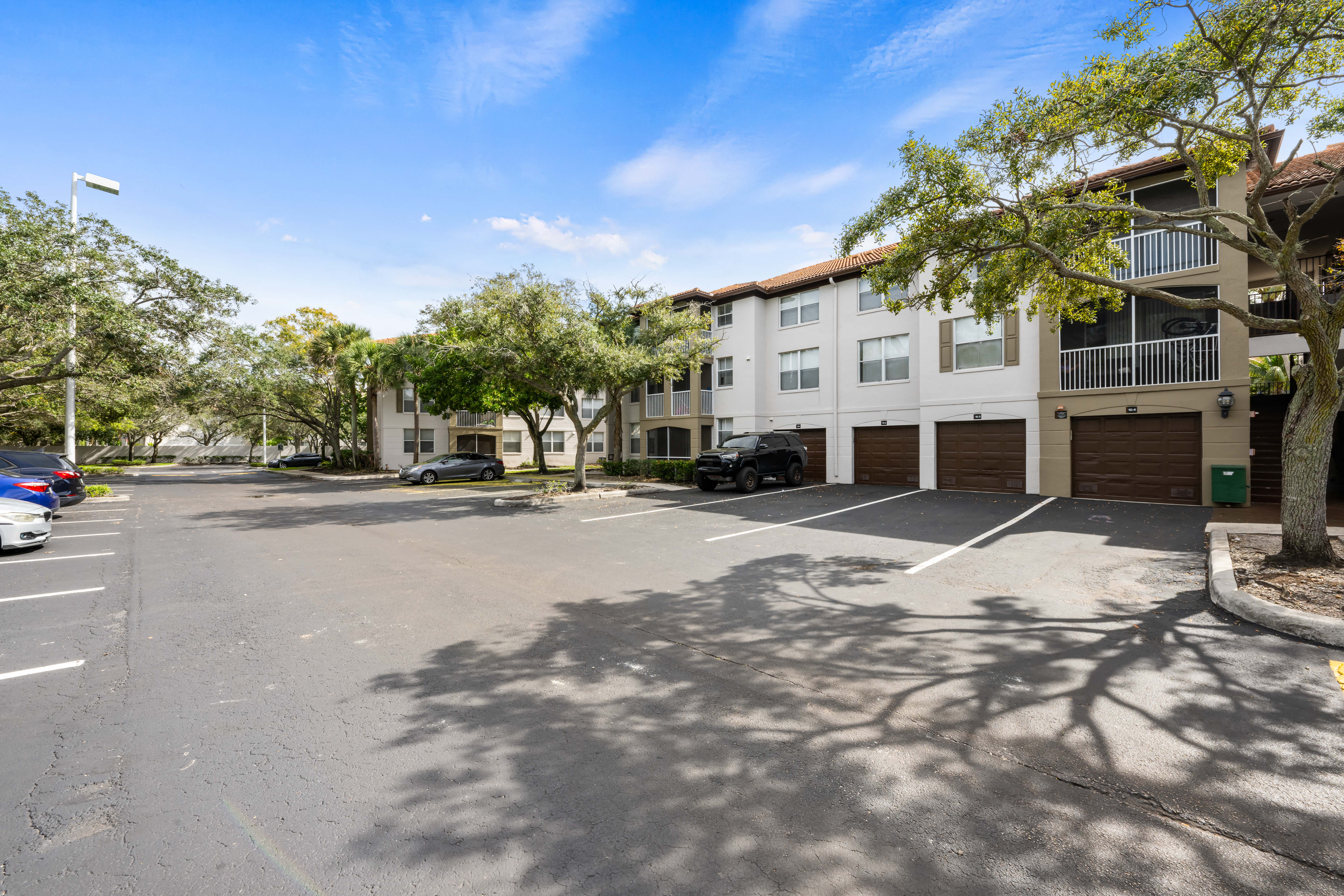 A parking lot in front of a building with cars parked.